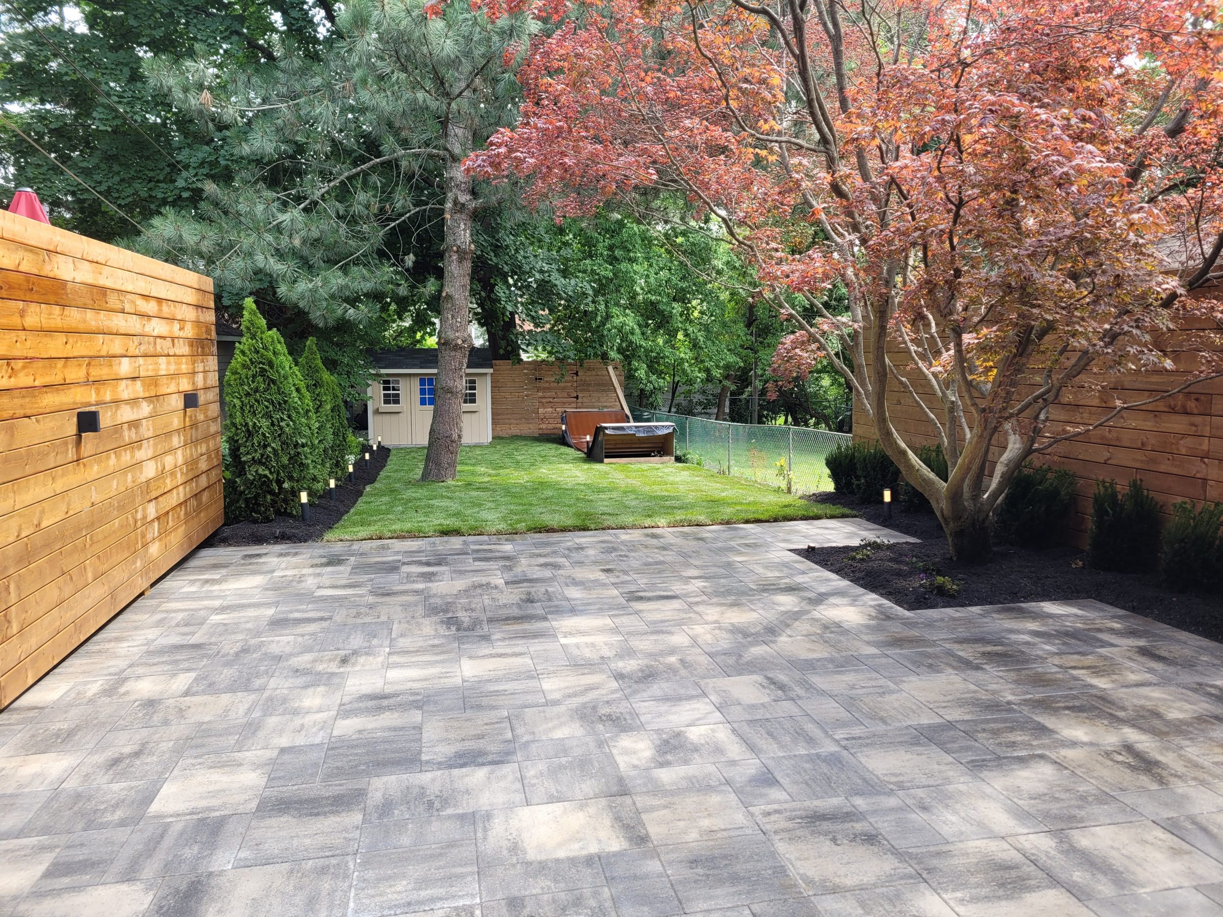 Backyard with trees, patio, and wooden fence.