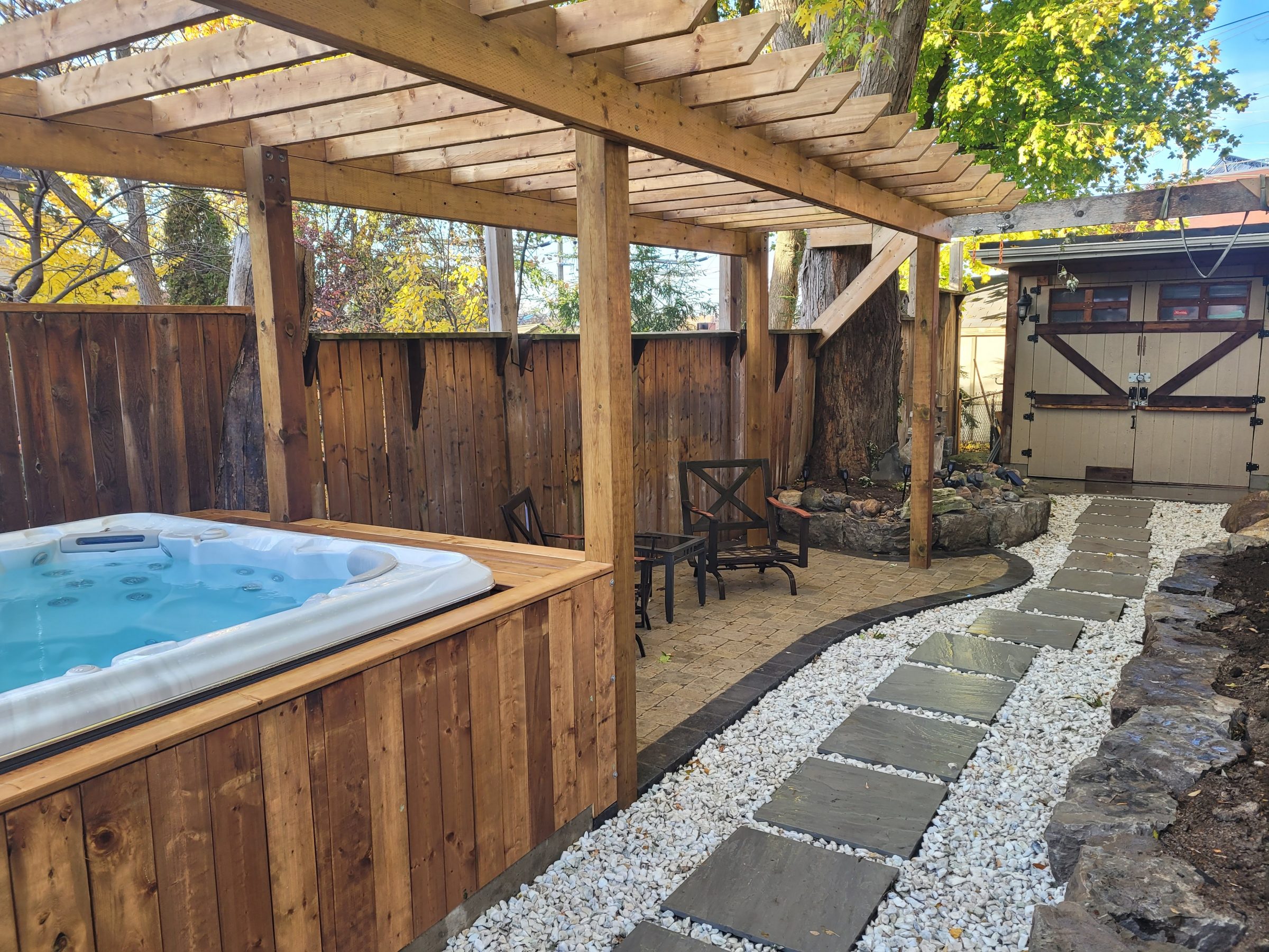 Backyard oasis with patio, hot tub, and path.