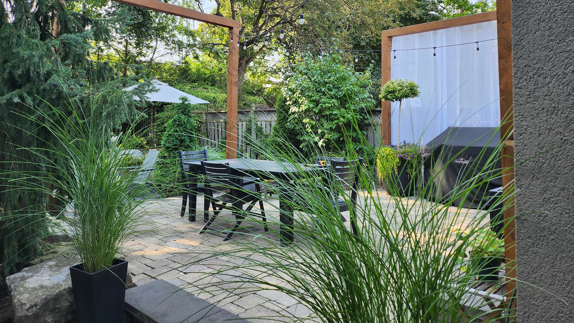 Cozy patio with table, chairs, and greenery.