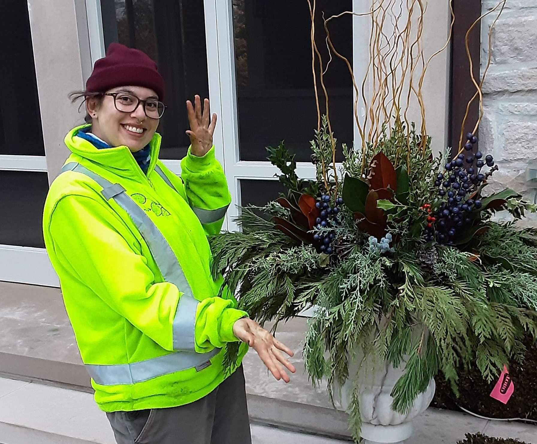 Person in bright jacket showcasing decorative plant arrangement.
