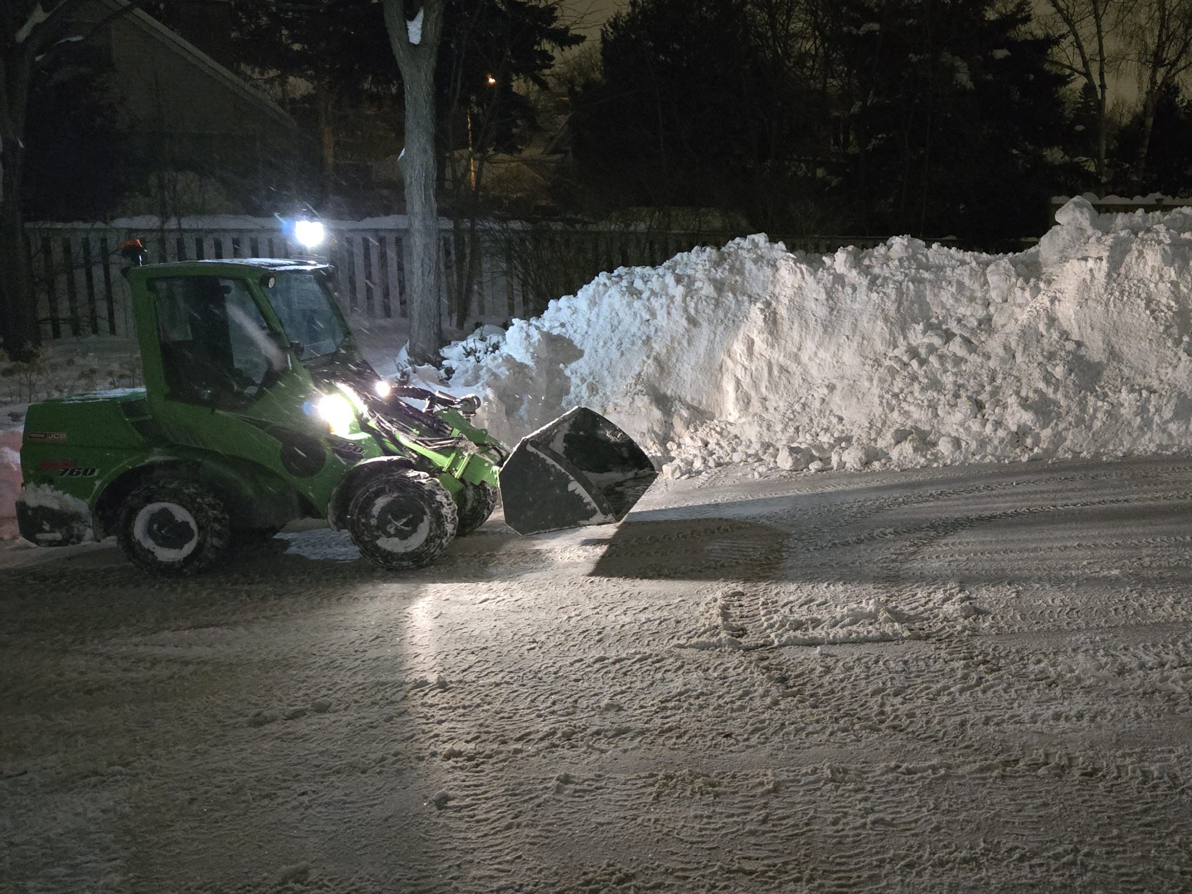 Tractor clearing snow at night on driveway.