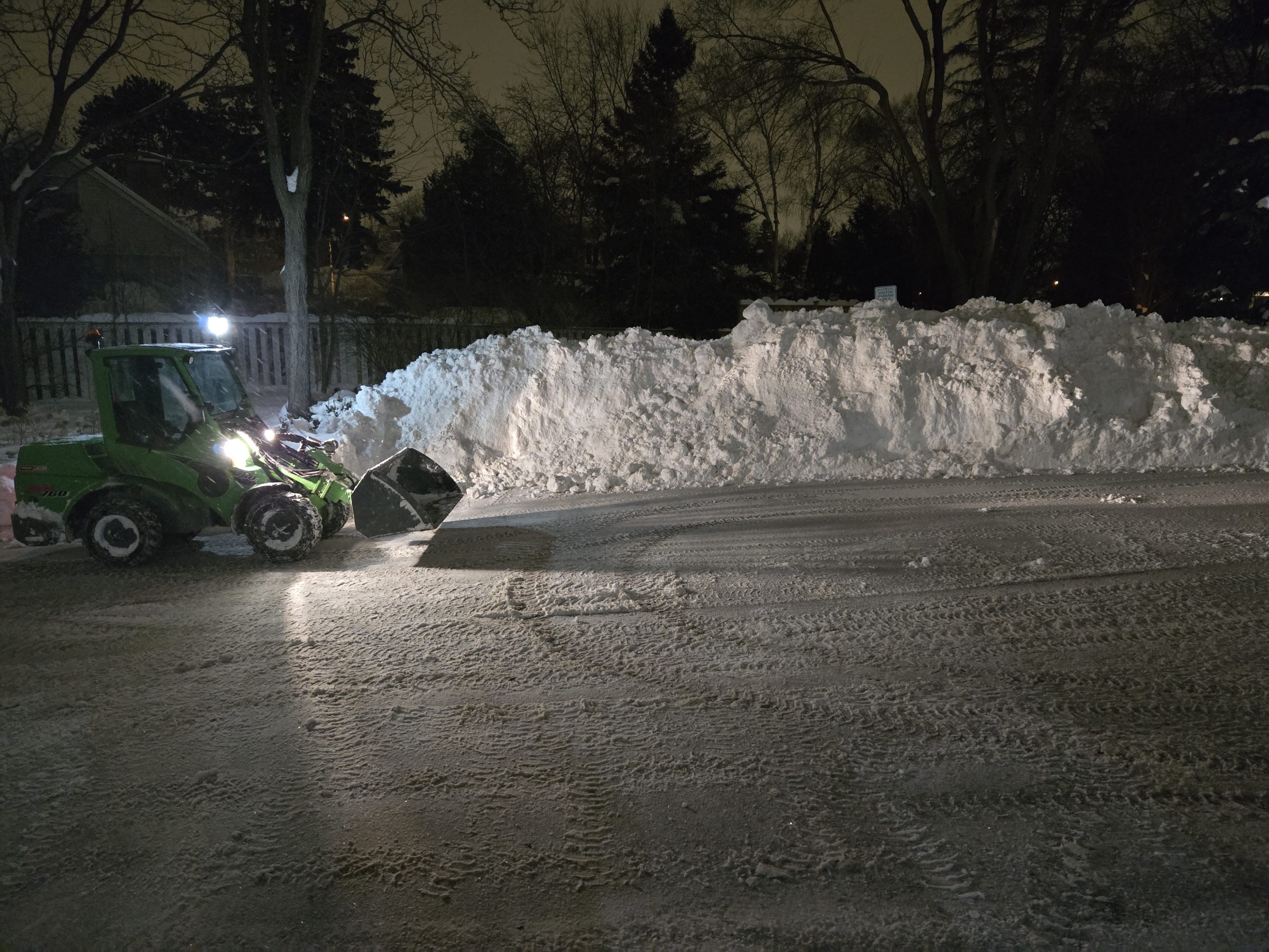 Snow plow clearing snowy road at night