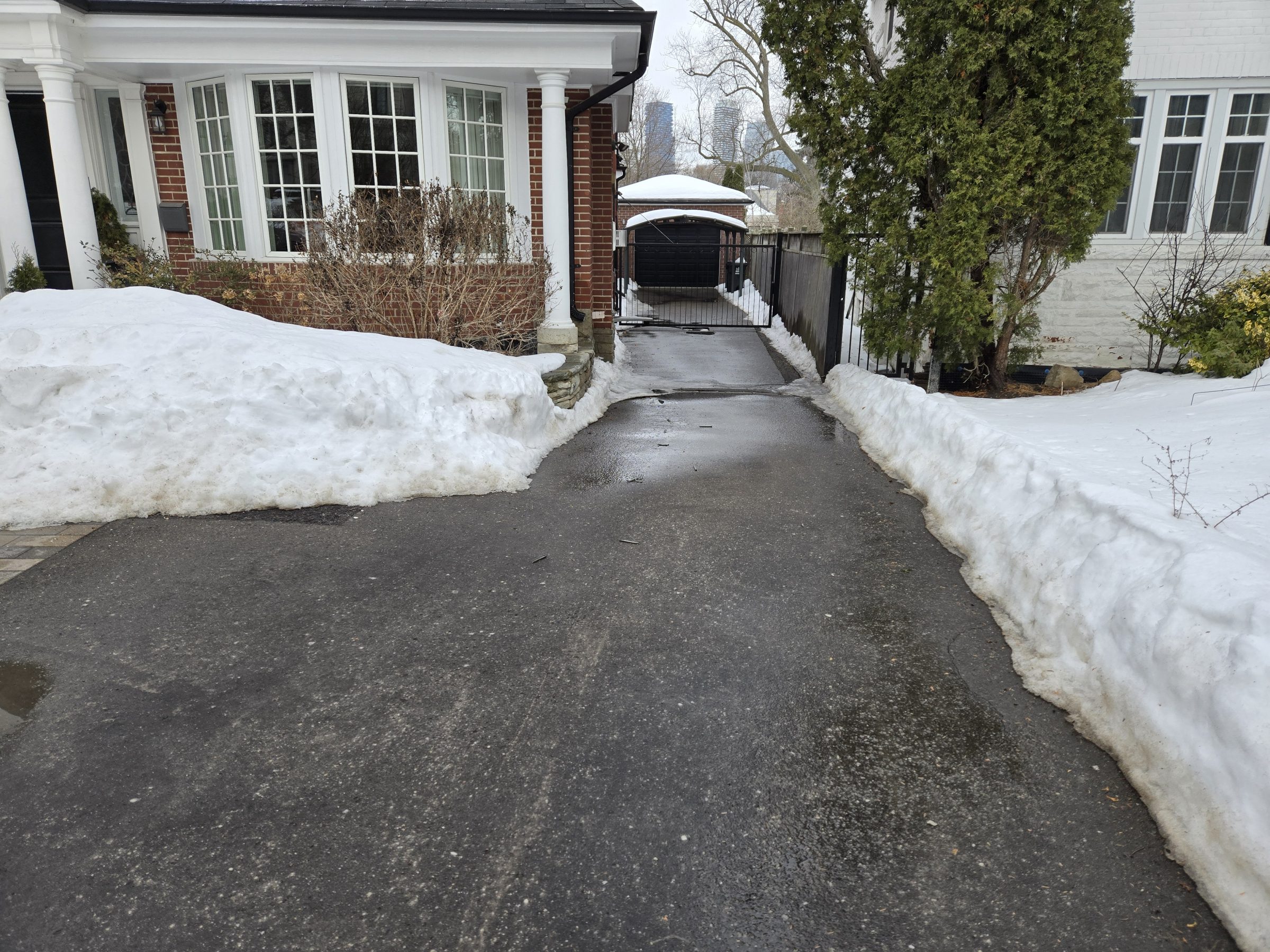 Snowy driveway between two houses in winter.