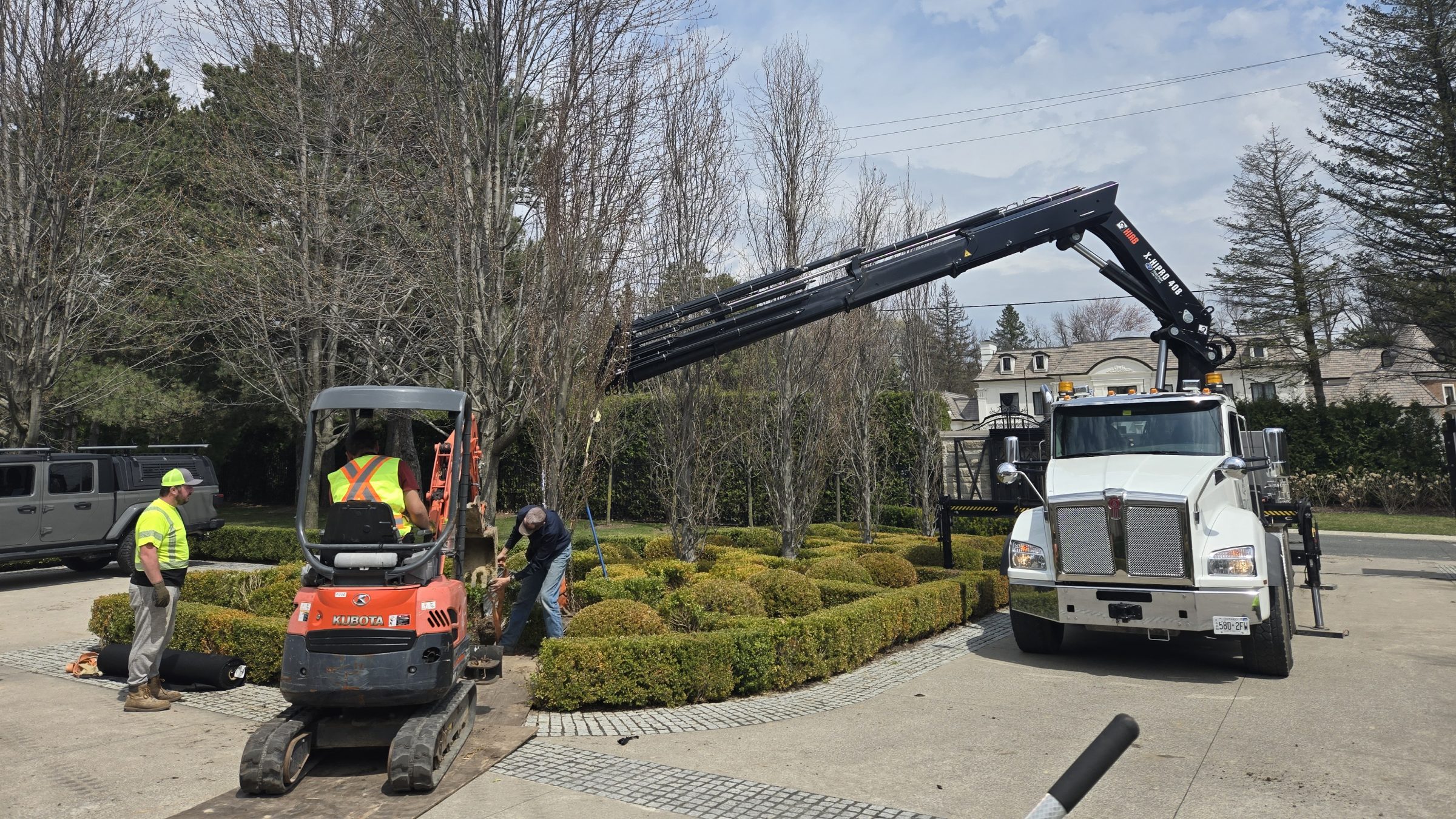 Workers with machinery landscaping residential driveway.