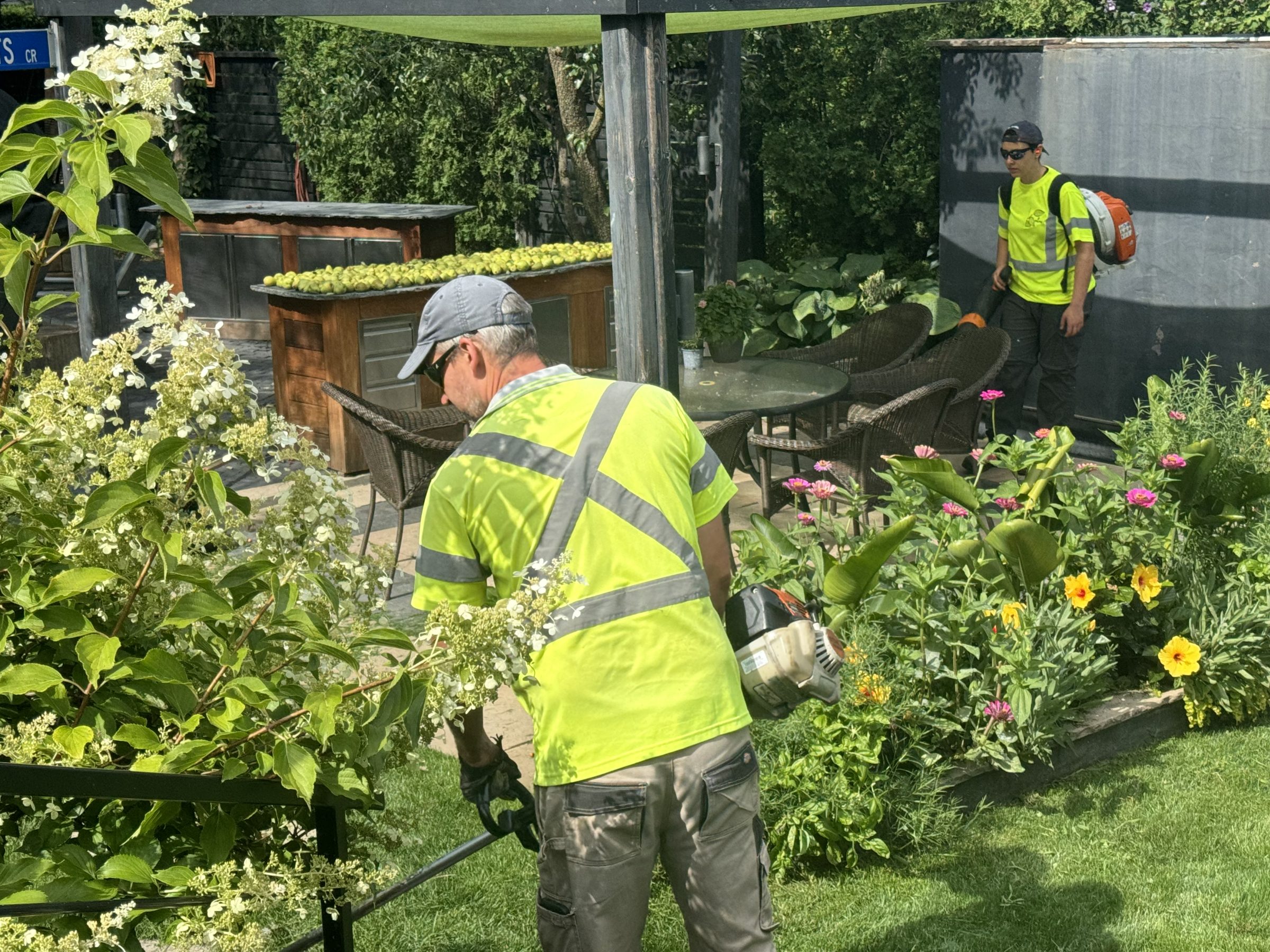 Gardeners in reflective vests tending to colorful garden.