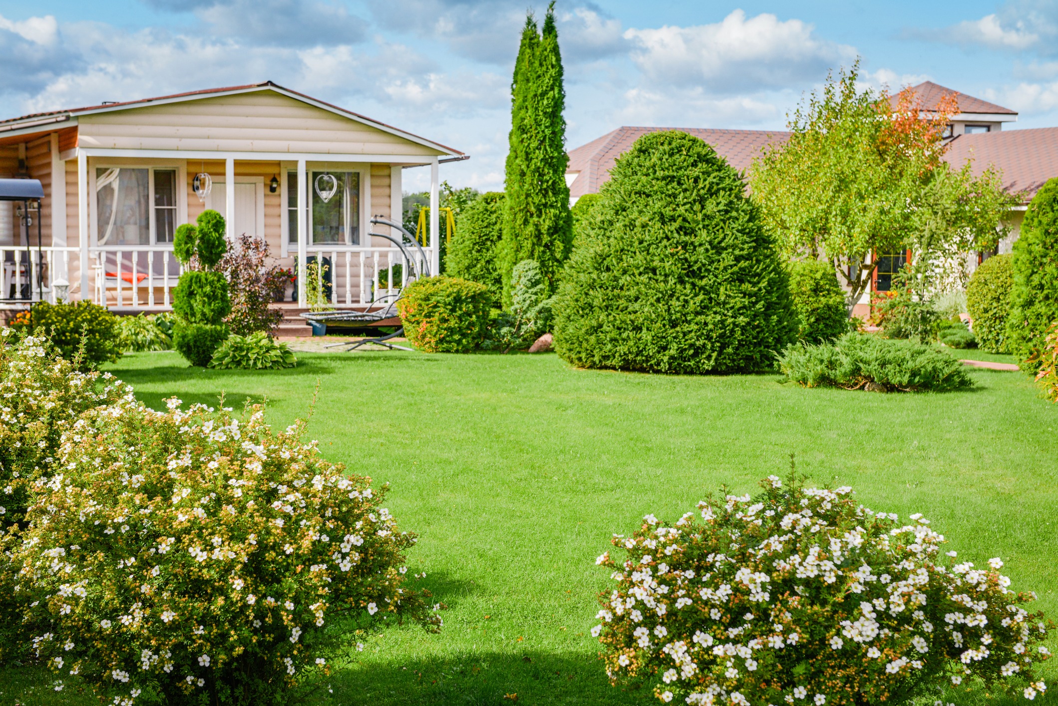 Cozy cottage surrounded by lush garden and lawn.