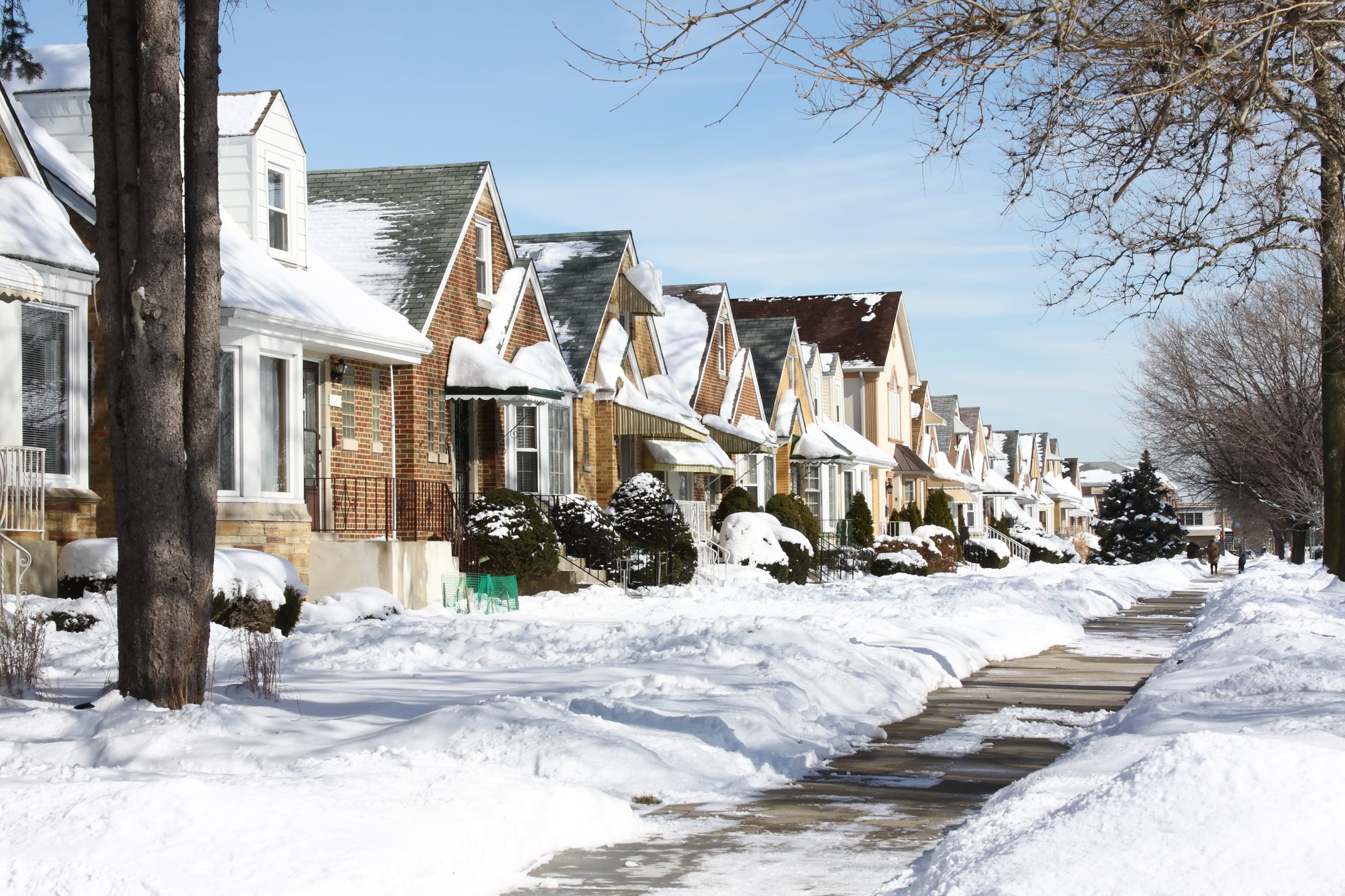 Snow-covered houses along suburban street in winter.