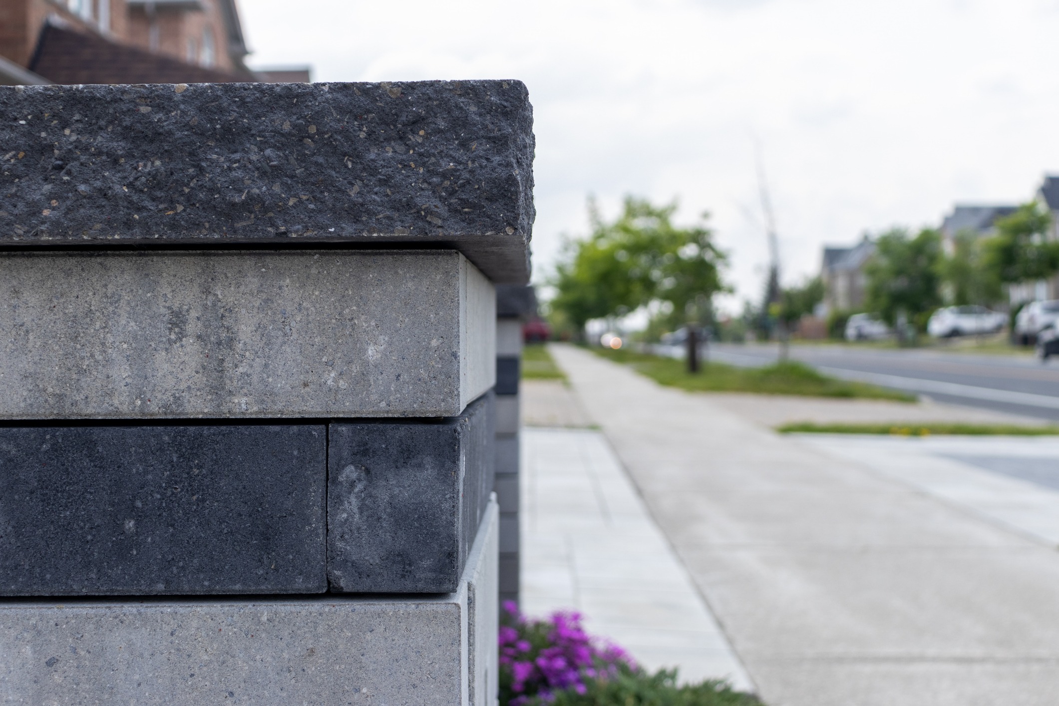 Concrete wall beside sidewalk with street view.
