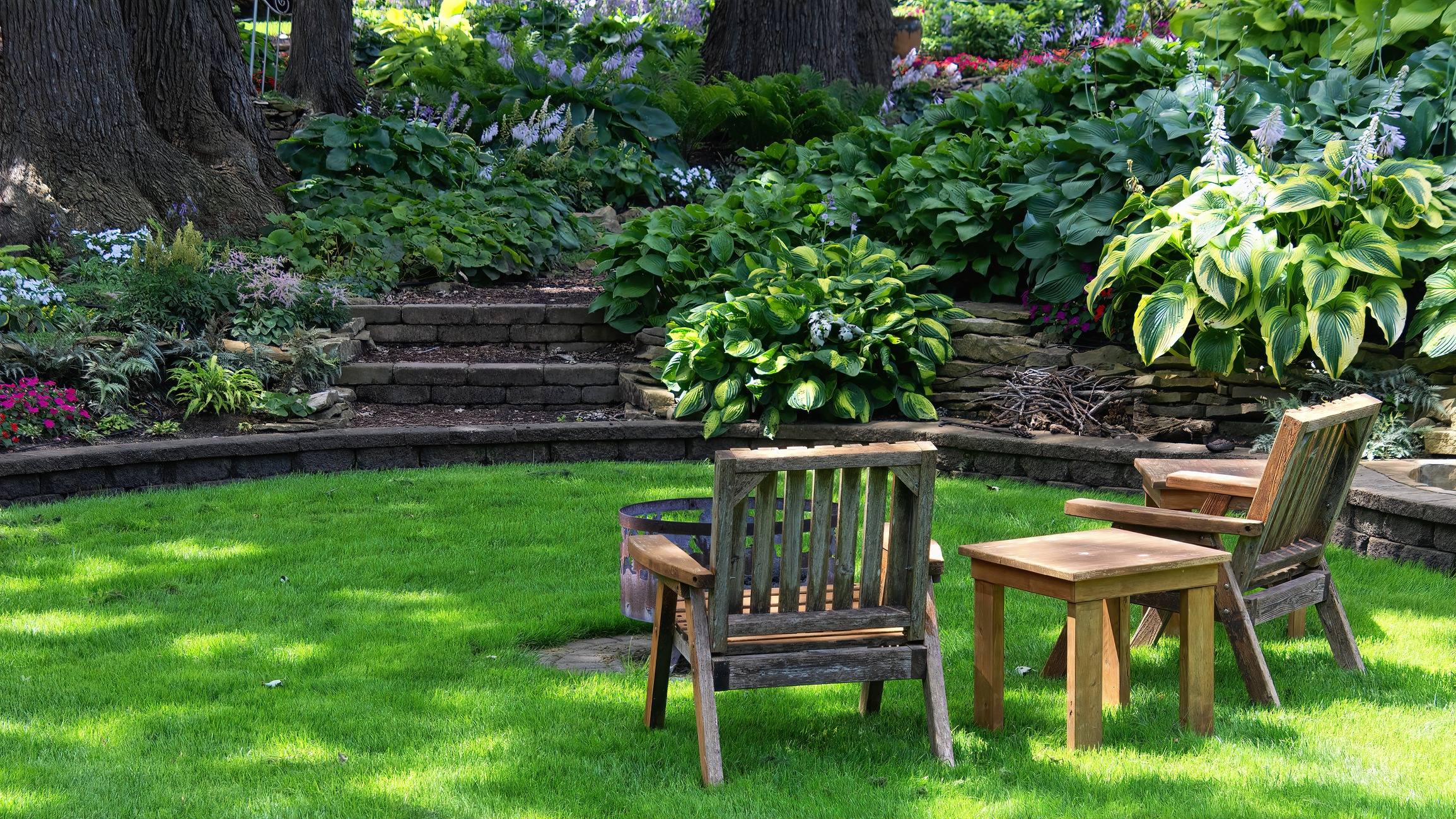 Wooden chairs in a lush garden setting.
